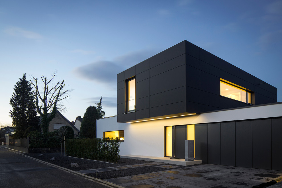 На фото: двухэтажный, черный дом в стиле модернизм с плоской крышей