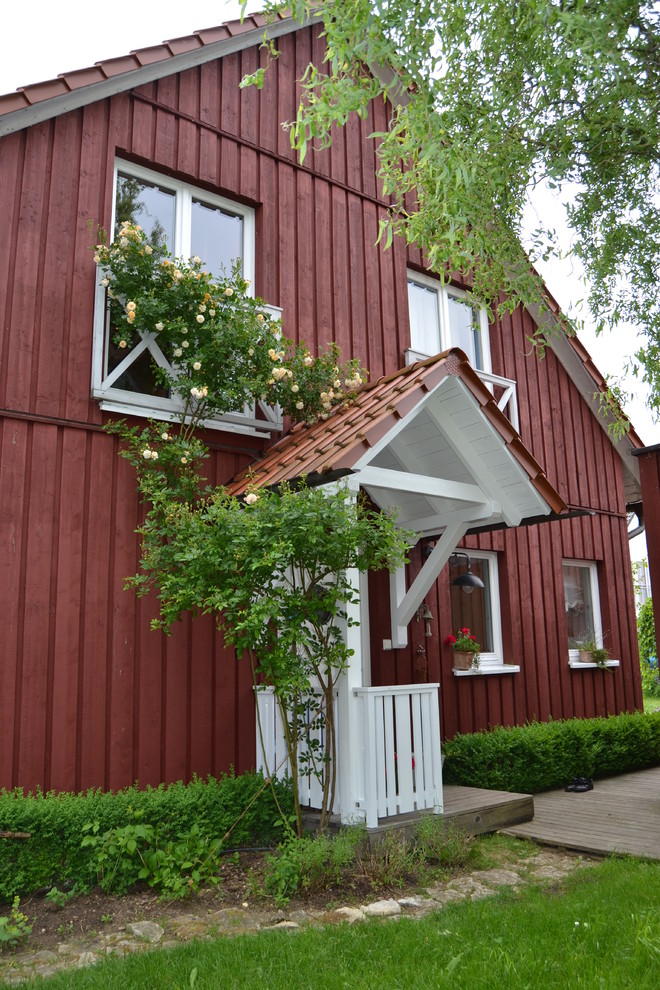 Foto della villa grande rossa country a due piani con rivestimento in legno, tetto a capanna e copertura in tegole