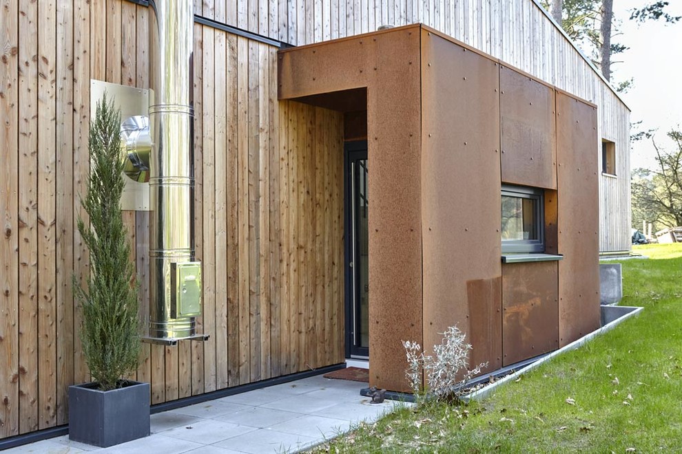 This is an example of a brown contemporary house exterior in Hamburg with wood cladding.