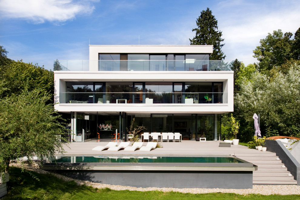 Immagine della facciata di una casa ampia bianca contemporanea a tre piani con rivestimento in vetro e tetto piano