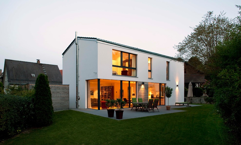 На фото: большой, двухэтажный, белый частный загородный дом в современном стиле с облицовкой из цементной штукатурки, двускатной крышей, черепичной крышей и серой крышей с