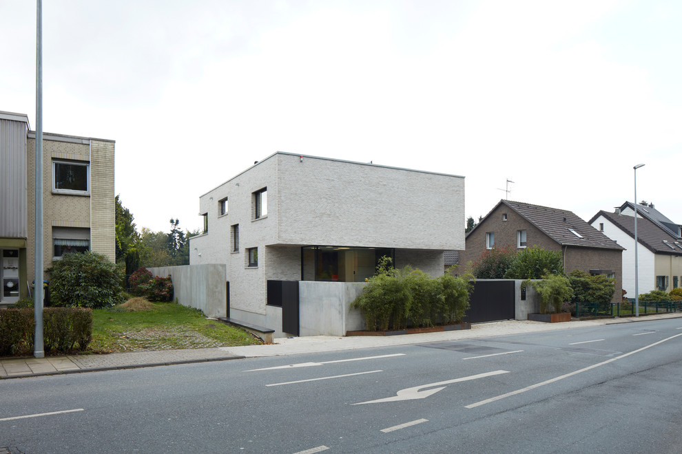 Immagine della facciata di una casa grande beige moderna a due piani con rivestimento in mattoni e tetto piano
