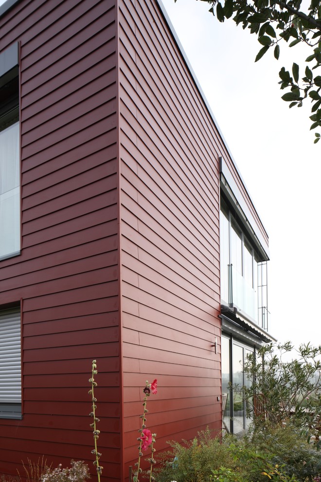 Foto de fachada de casa roja contemporánea de tamaño medio de dos plantas con revestimiento de aglomerado de cemento y tejado plano