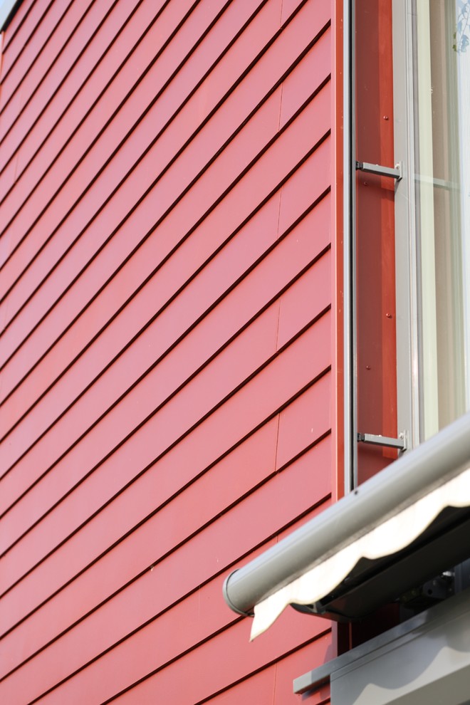 На фото: двухэтажный, красный частный загородный дом среднего размера в современном стиле с облицовкой из ЦСП и плоской крышей с