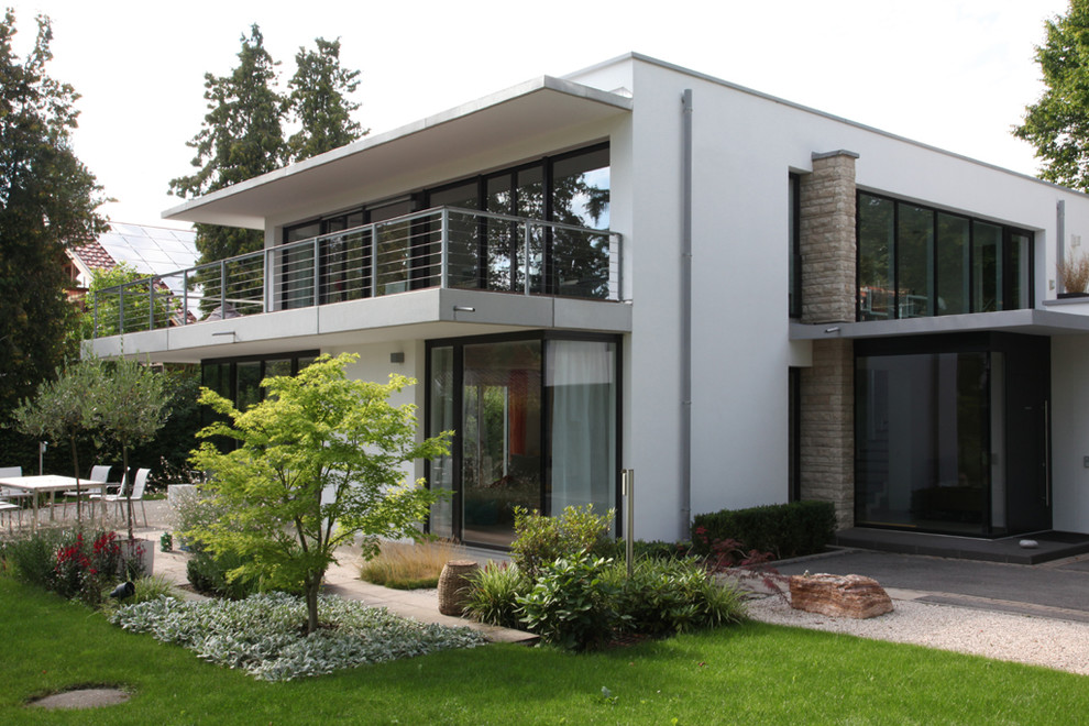 Diseño de fachada de casa blanca actual de dos plantas con revestimiento de estuco y tejado plano
