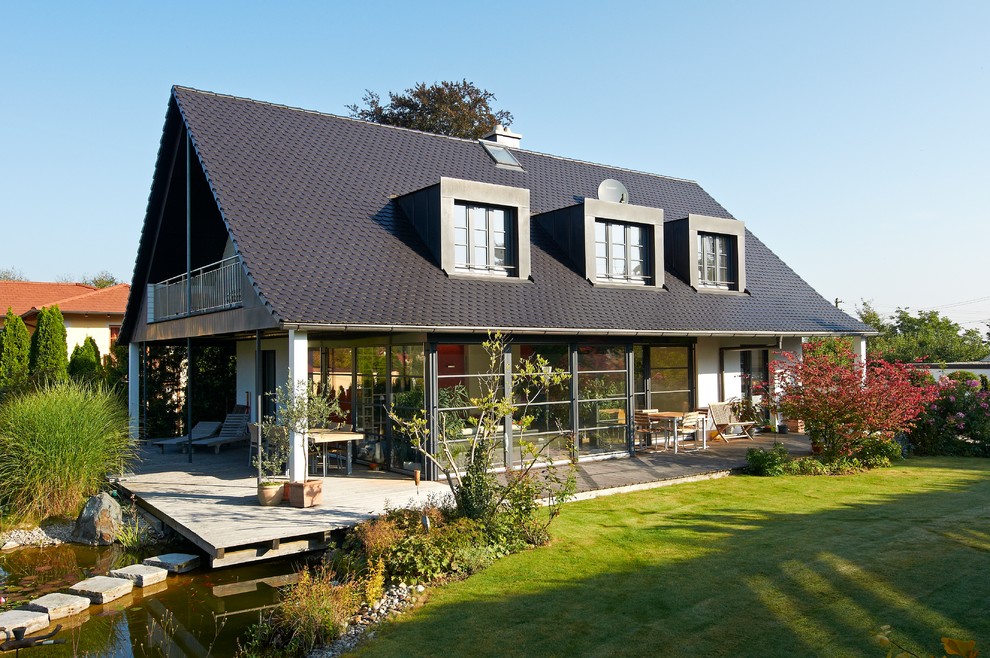 Imagen de fachada de casa blanca tradicional de tamaño medio de dos plantas con revestimiento de vidrio, tejado a dos aguas y tejado de teja de barro