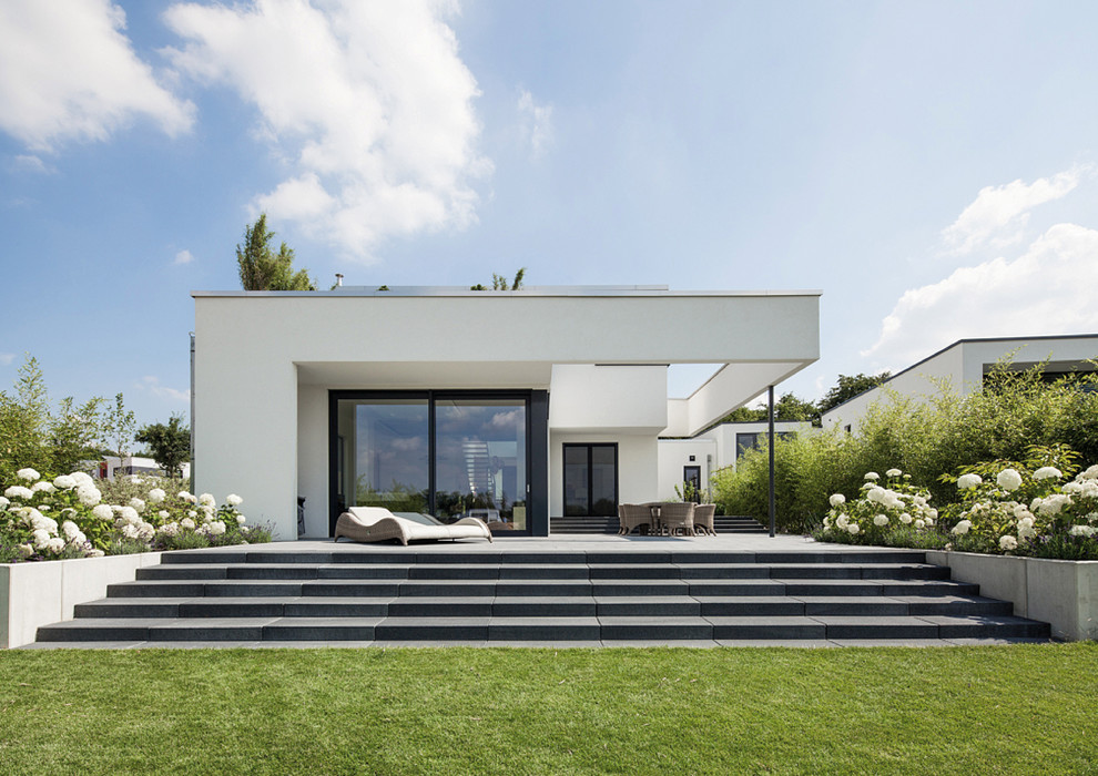 Cette image montre une façade de maison blanche minimaliste de plain-pied et de taille moyenne avec un toit plat.