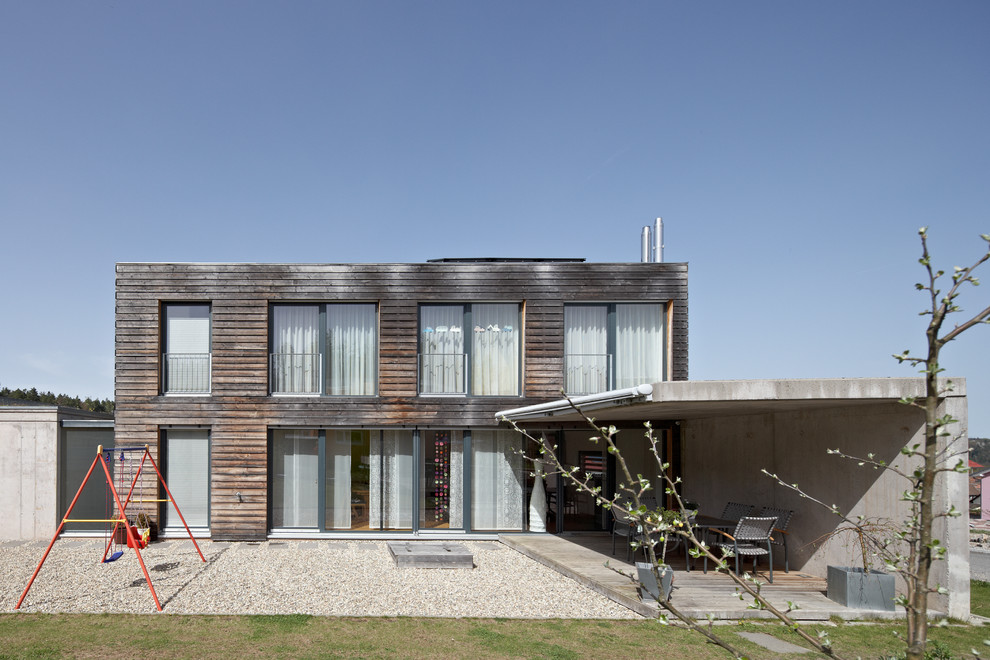 На фото: двухэтажный, деревянный, коричневый дом среднего размера в современном стиле с плоской крышей с