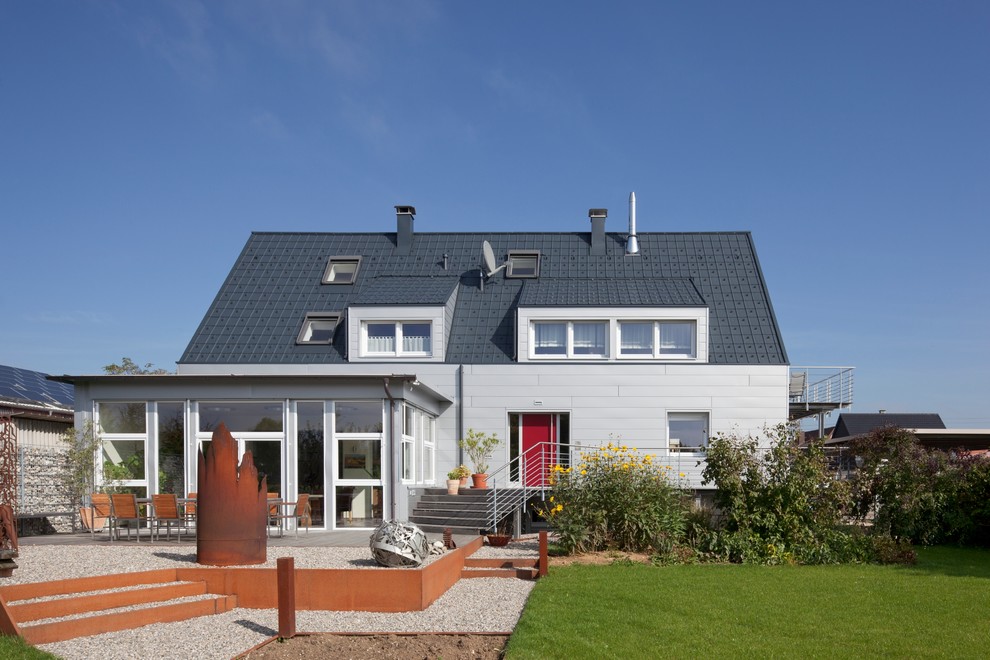 Стильный дизайн: серый, трехэтажный дом среднего размера в современном стиле с облицовкой из металла и двускатной крышей - последний тренд