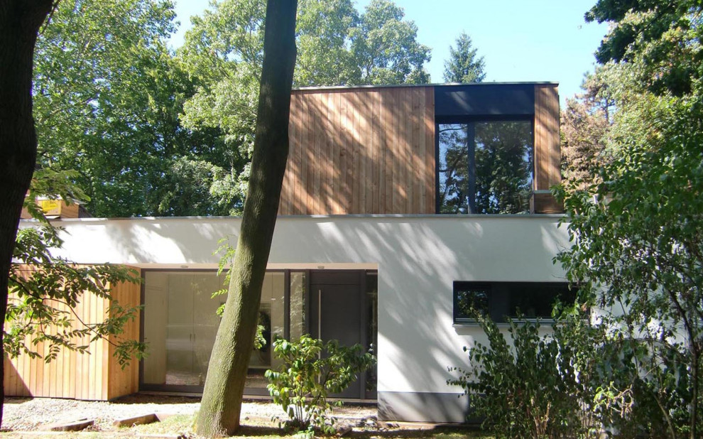 Inspiration for a white modern detached house in Cologne with wood cladding, a flat roof and shiplap cladding.