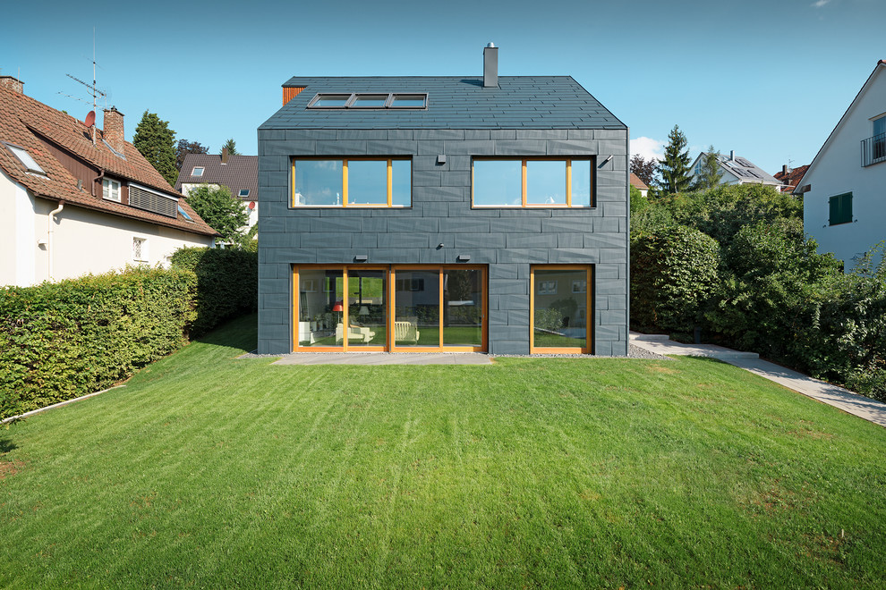 Modelo de fachada negra actual de tamaño medio de tres plantas con revestimiento de metal y tejado a dos aguas