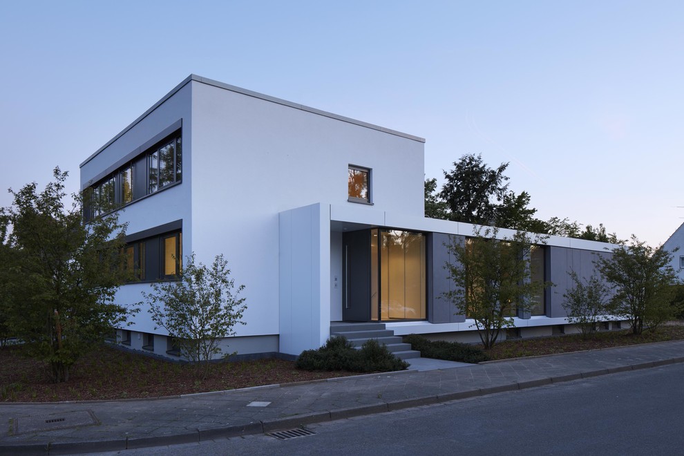 Mittelgroßes, Dreistöckiges Modernes Einfamilienhaus mit Mix-Fassade, weißer Fassadenfarbe und Flachdach in Düsseldorf