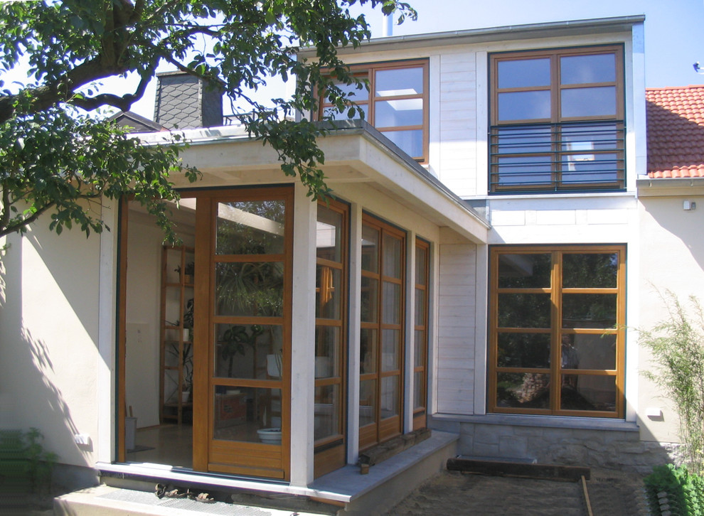 Modelo de fachada blanca contemporánea pequeña de dos plantas con revestimiento de madera