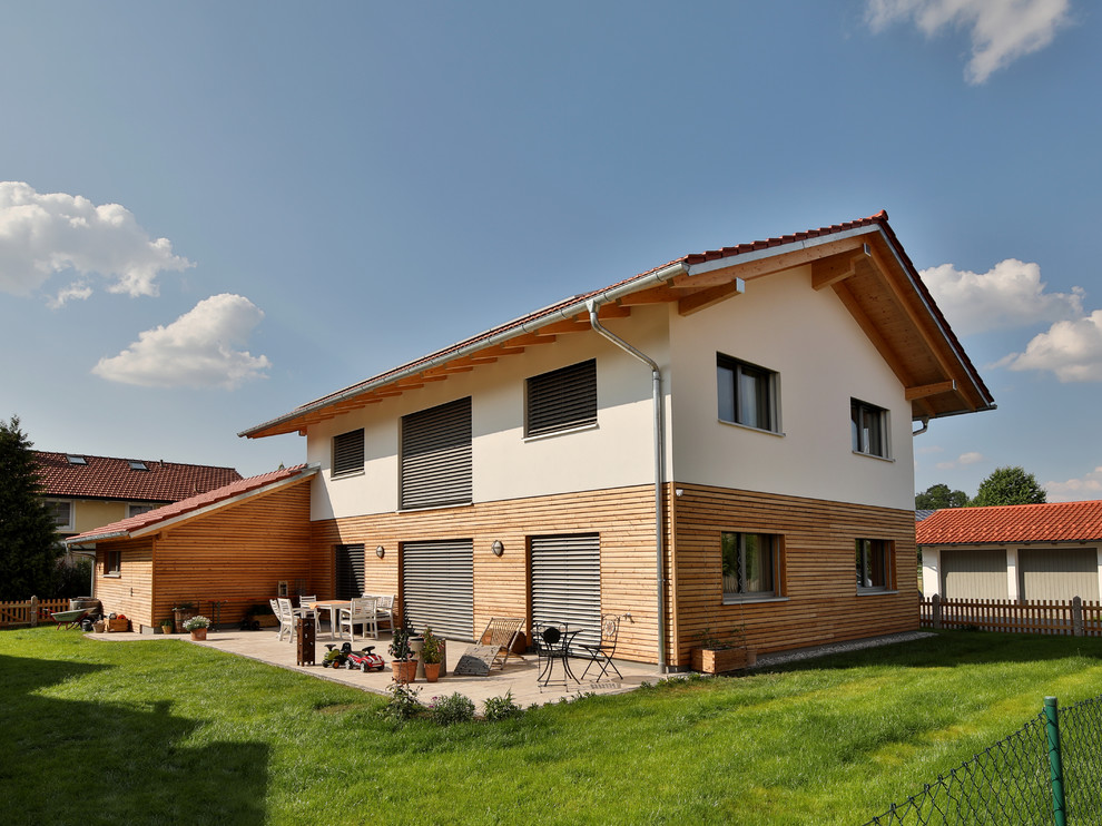 Medium sized and white contemporary two floor detached house in Munich with mixed cladding, a pitched roof and a tiled roof.