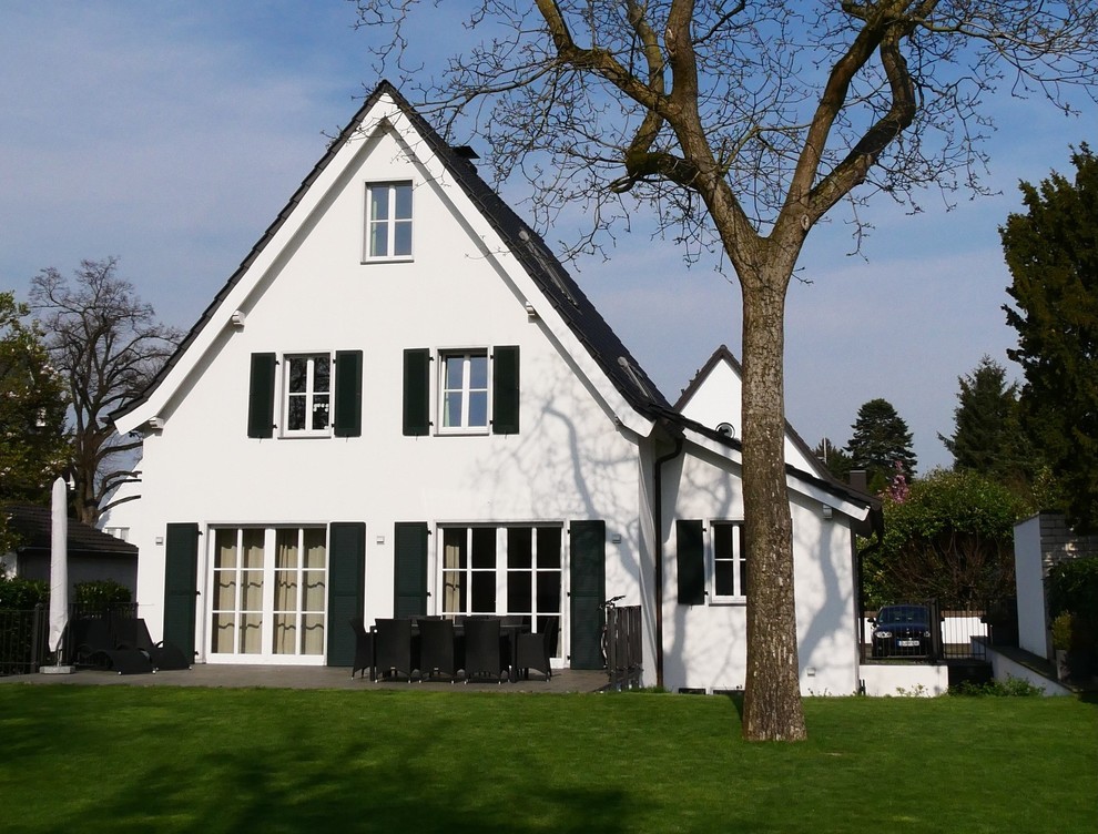 Inredning av ett modernt mellanstort vitt hus, med tre eller fler plan, stuckatur, sadeltak och tak med takplattor