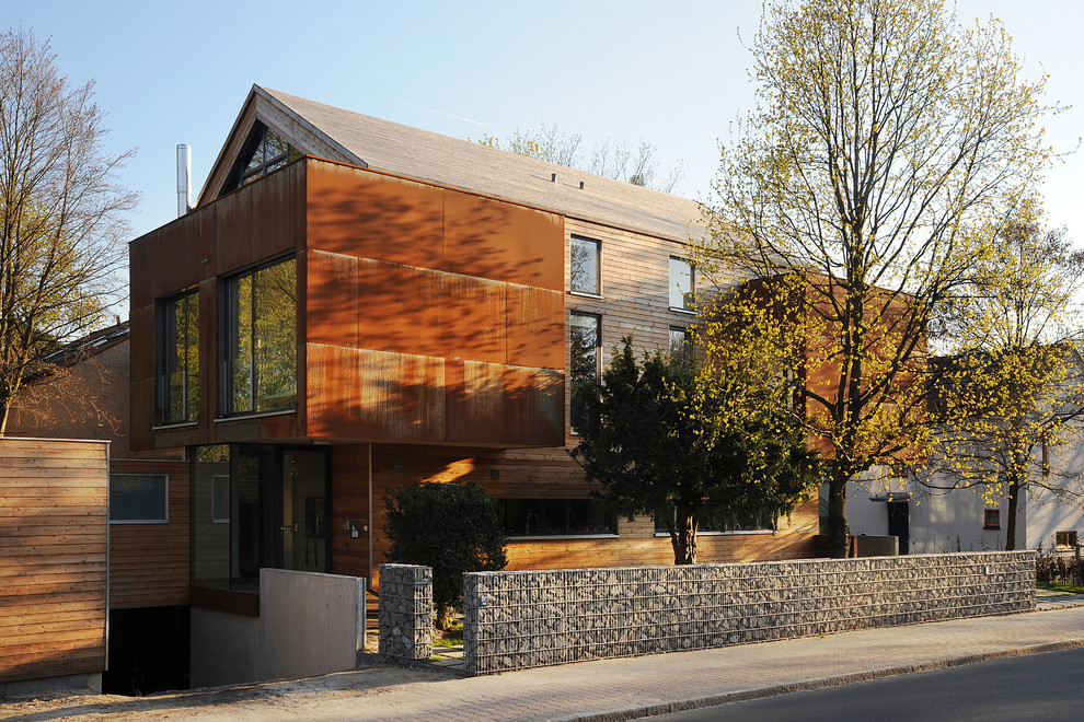 Foto de fachada marrón actual de tamaño medio de tres plantas con revestimientos combinados y tejado a dos aguas