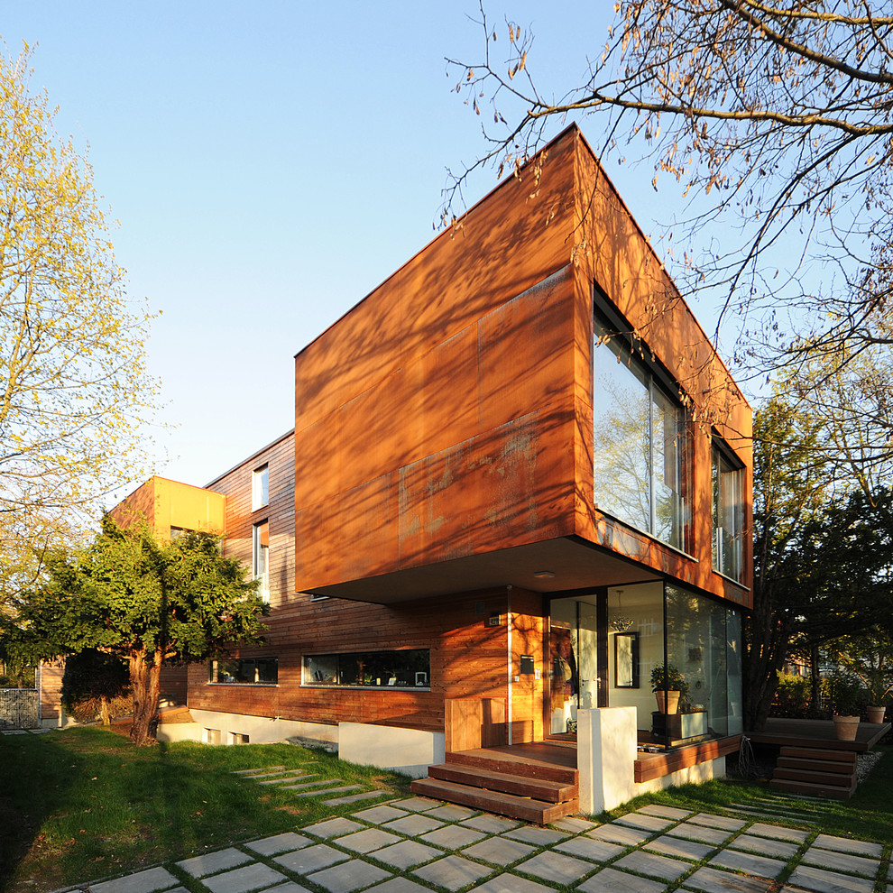 На фото: двухэтажный, коричневый дом среднего размера в современном стиле с комбинированной облицовкой и плоской крышей с