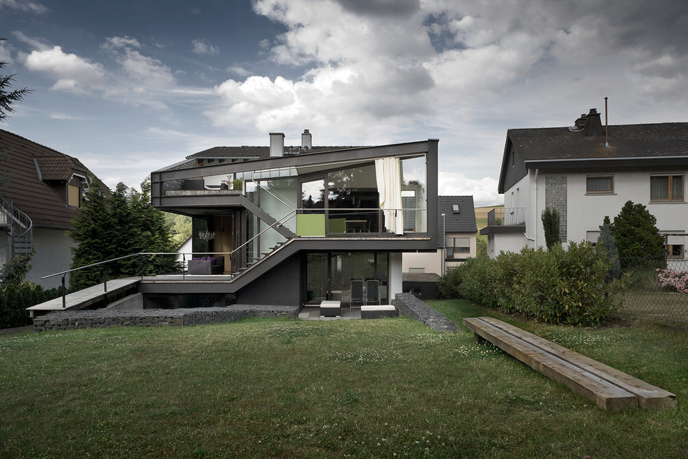 Inspiration för mellanstora moderna svarta hus, med två våningar, glasfasad och pulpettak