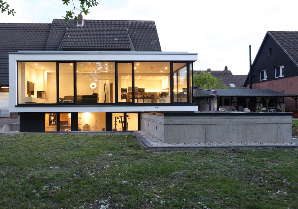 Zweistöckiges, Mittelgroßes Modernes Einfamilienhaus mit Glasfassade, weißer Fassadenfarbe und Flachdach in Sonstige