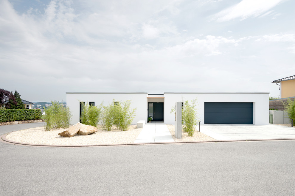 Cette photo montre une façade de maison blanche tendance en stuc de plain-pied et de taille moyenne avec un toit plat.