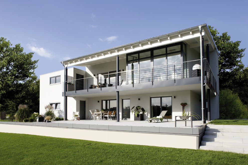 Réalisation d'une grande façade de maison blanche design à un étage avec un toit en appentis.