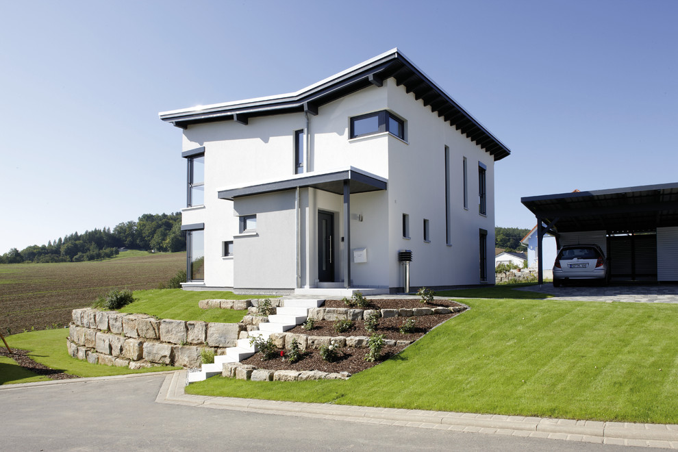 Imagen de fachada de casa blanca actual de dos plantas con revestimiento de estuco