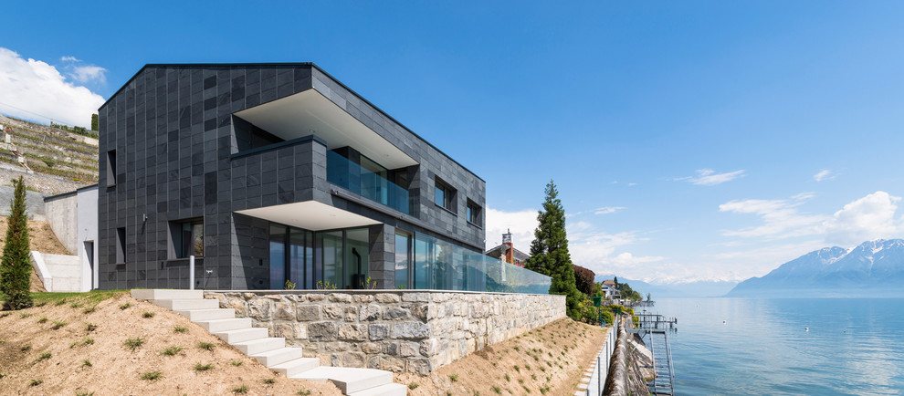 Inspiration för mellanstora moderna grå stenhus, med två våningar och pulpettak