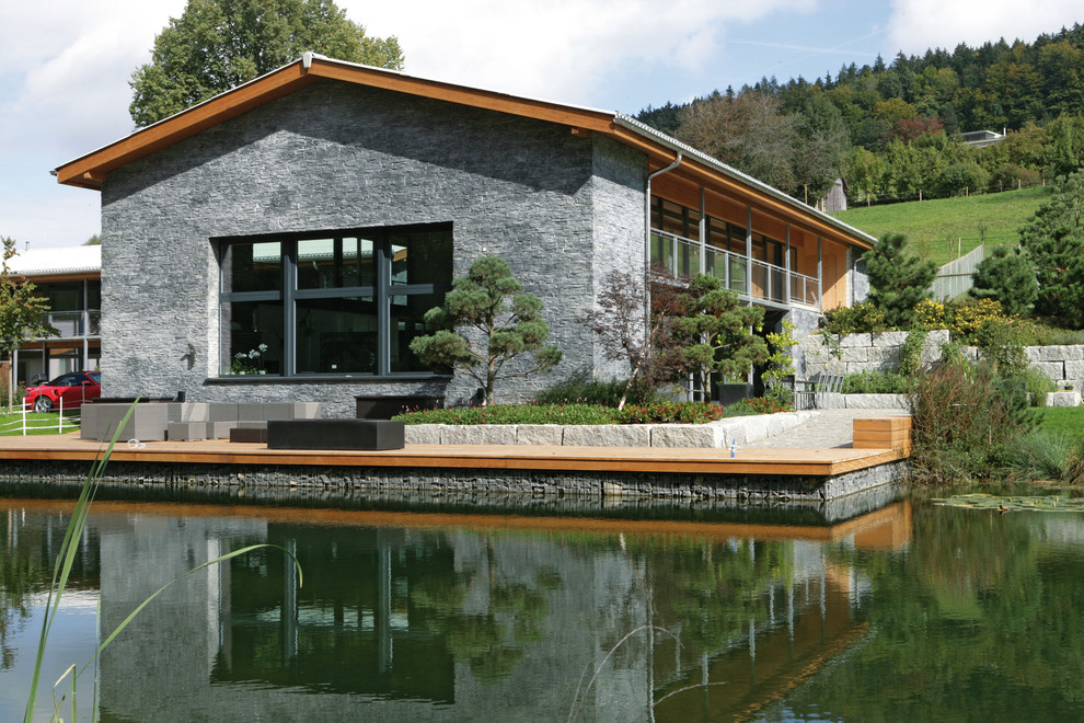 Diseño de fachada gris rural de tamaño medio de dos plantas con revestimiento de piedra y tejado a dos aguas
