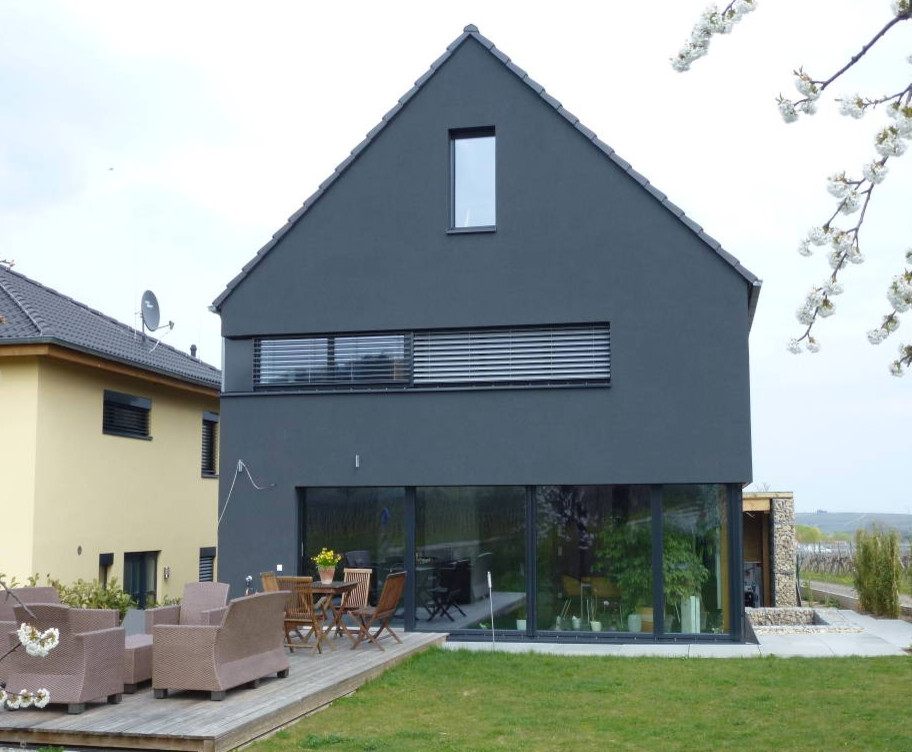 Zweistöckiges Modernes Haus mit Betonfassade, grauer Fassadenfarbe und Satteldach in Sonstige