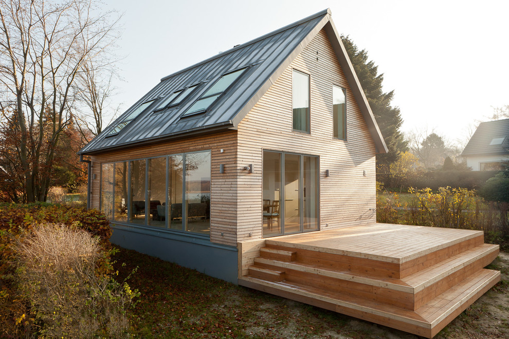 Esempio della facciata di una casa piccola marrone contemporanea a due piani con rivestimento in legno e tetto a capanna