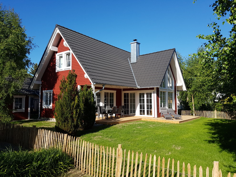 Пример оригинального дизайна: маленький, одноэтажный, деревянный, красный частный загородный дом в скандинавском стиле с двускатной крышей и черепичной крышей для на участке и в саду