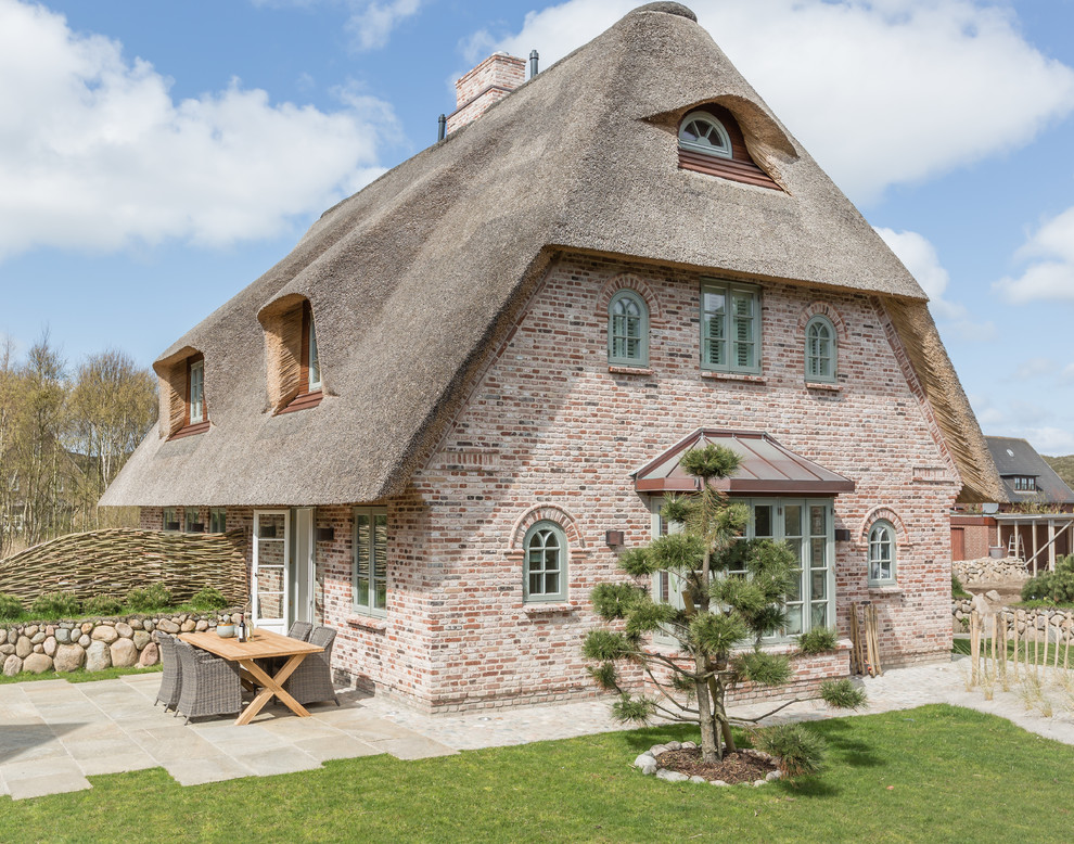 Idée de décoration pour une façade de maison rouge champêtre en brique à deux étages et plus et de taille moyenne avec un toit à croupette.