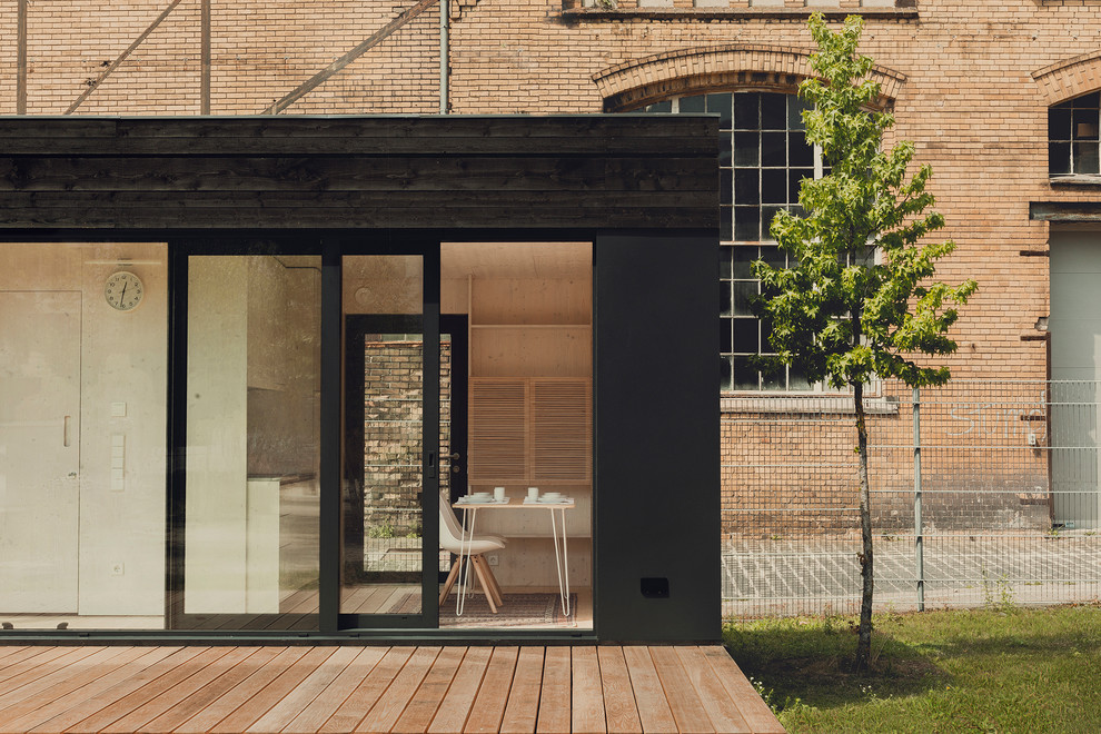 Small and black contemporary bungalow house exterior in Berlin with wood cladding and a flat roof.