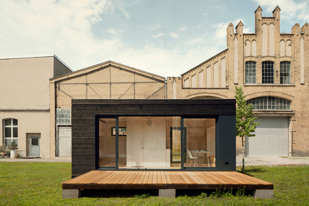 Стильный дизайн: маленький, одноэтажный, деревянный, черный дом в современном стиле с плоской крышей для на участке и в саду - последний тренд