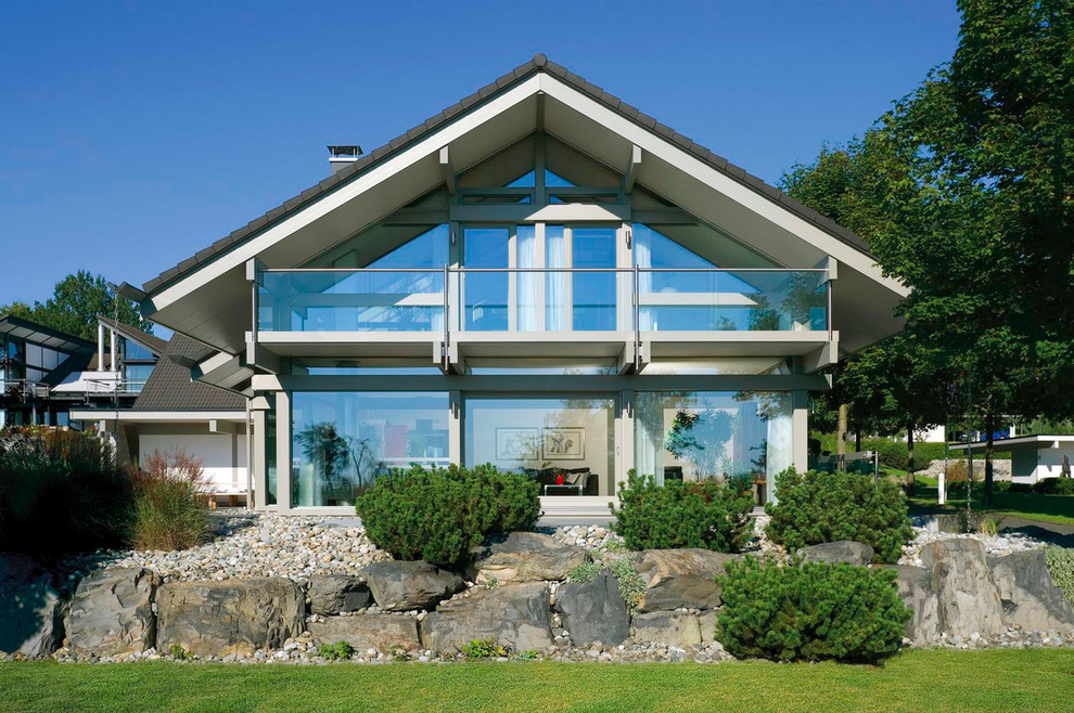Foto de fachada actual de tamaño medio de dos plantas con revestimiento de vidrio y tejado a dos aguas