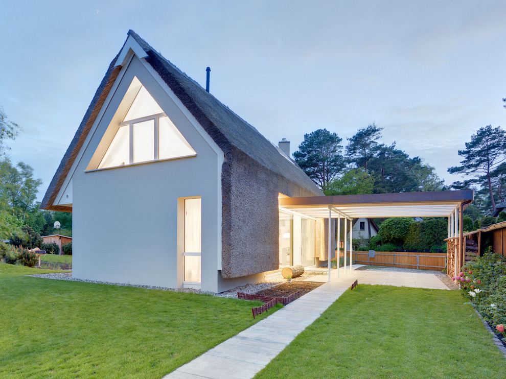 На фото: маленький, двухэтажный, белый дом в современном стиле с двускатной крышей и комбинированной облицовкой для на участке и в саду