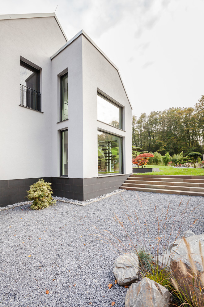 Стильный дизайн: двухэтажный, белый дом среднего размера в современном стиле с облицовкой из цементной штукатурки и двускатной крышей - последний тренд
