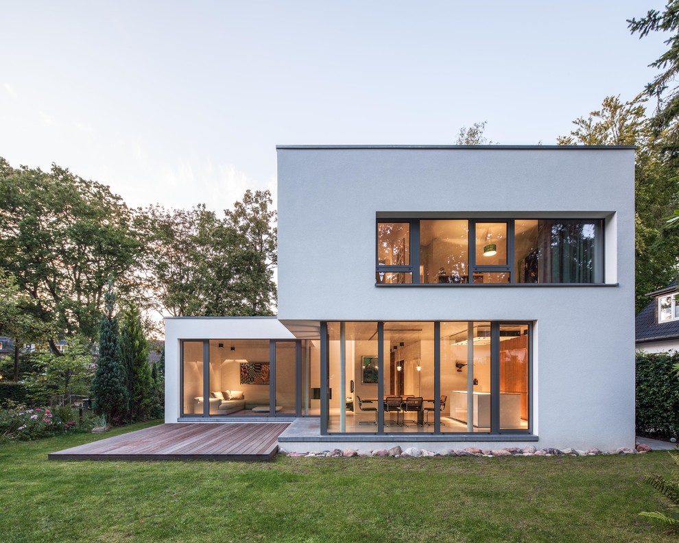 На фото: двухэтажный, белый дом среднего размера в современном стиле с плоской крышей и облицовкой из цементной штукатурки