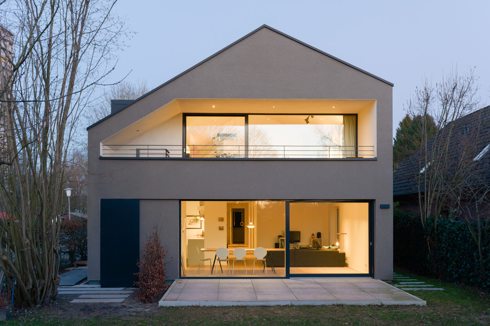 Пример оригинального дизайна: большой, двухэтажный, коричневый дуплекс в стиле модернизм с облицовкой из цементной штукатурки, двускатной крышей и черепичной крышей