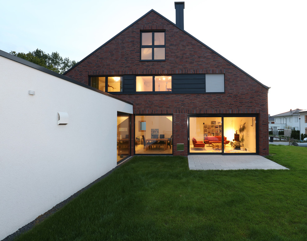 Großes, Dreistöckiges Country Einfamilienhaus mit Backsteinfassade, brauner Fassadenfarbe und Satteldach in Sonstige