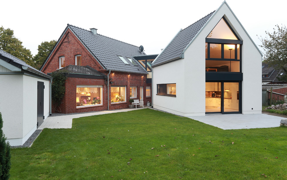 Réalisation d'une grande façade de maison multicolore design à un étage avec un revêtement mixte, un toit à deux pans et un toit en tuile.