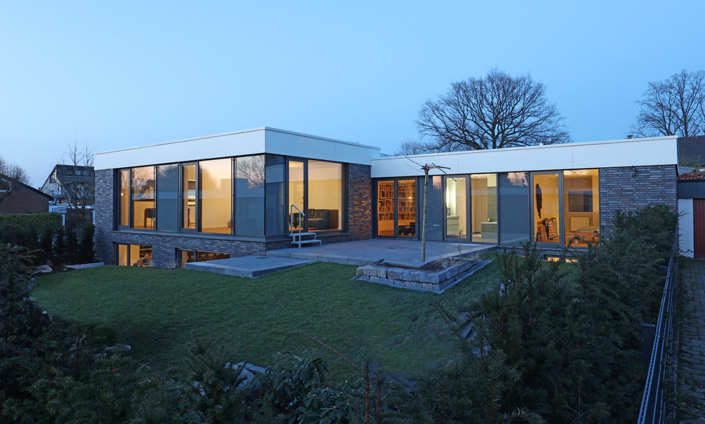 На фото: двухэтажный частный загородный дом среднего размера в стиле модернизм с комбинированной облицовкой и плоской крышей