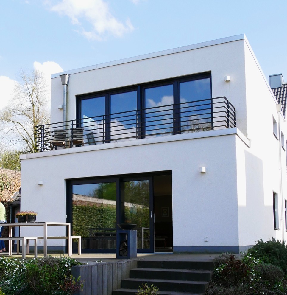 Mittelgroßes, Zweistöckiges Modernes Einfamilienhaus mit Putzfassade, weißer Fassadenfarbe, Satteldach und Ziegeldach in Düsseldorf