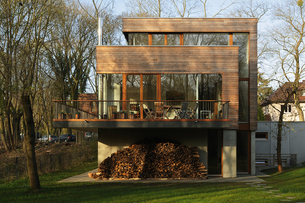 На фото: трехэтажный, деревянный, коричневый дом среднего размера в современном стиле с плоской крышей с