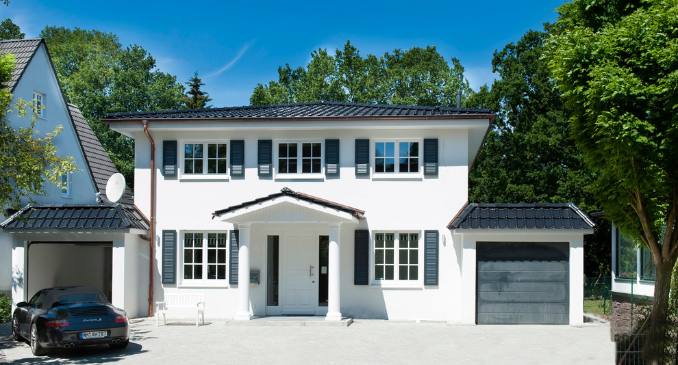 Photo of a medium sized and white world-inspired two floor house exterior in Hamburg with a hip roof.