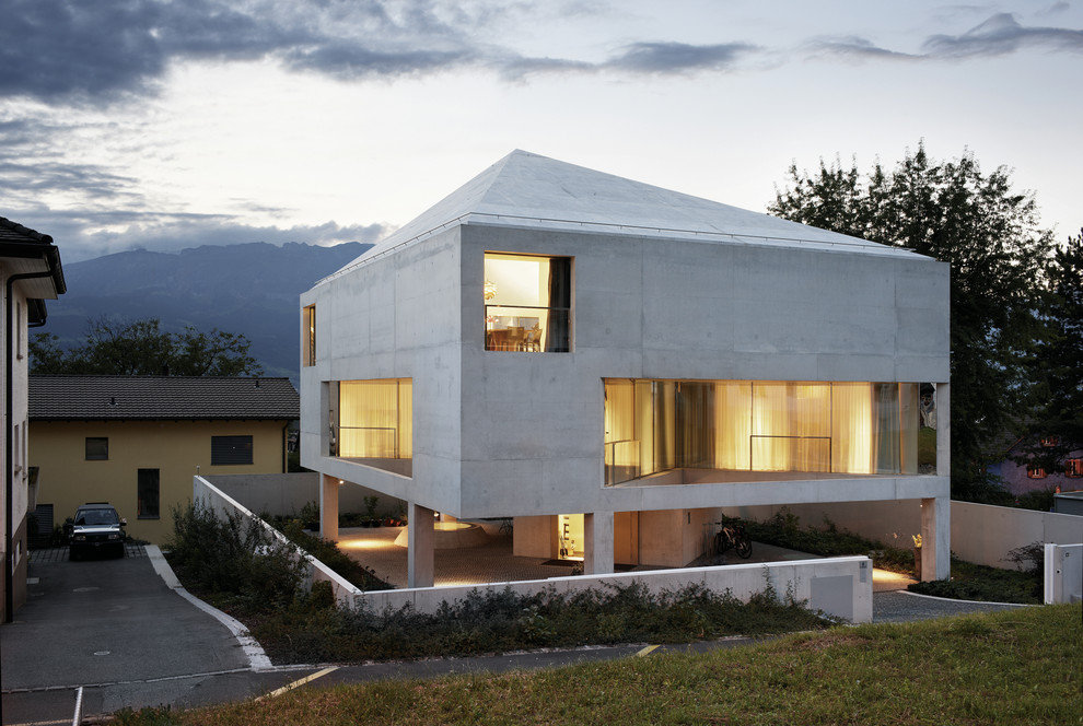 Idées déco pour une grande façade de maison grise contemporaine en béton à deux étages et plus avec un toit à quatre pans.