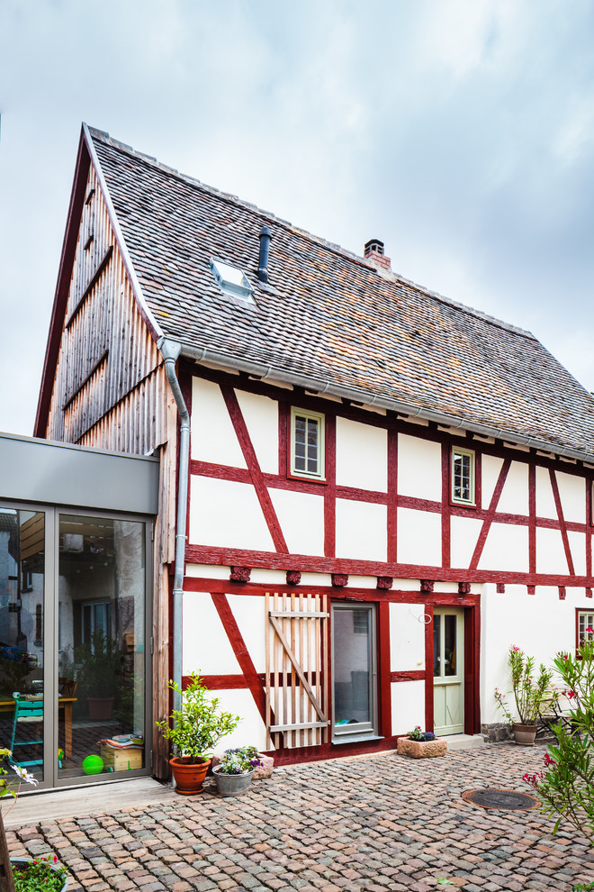 Medium sized and white rural detached house in Frankfurt with three floors, mixed cladding, a pitched roof and a shingle roof.