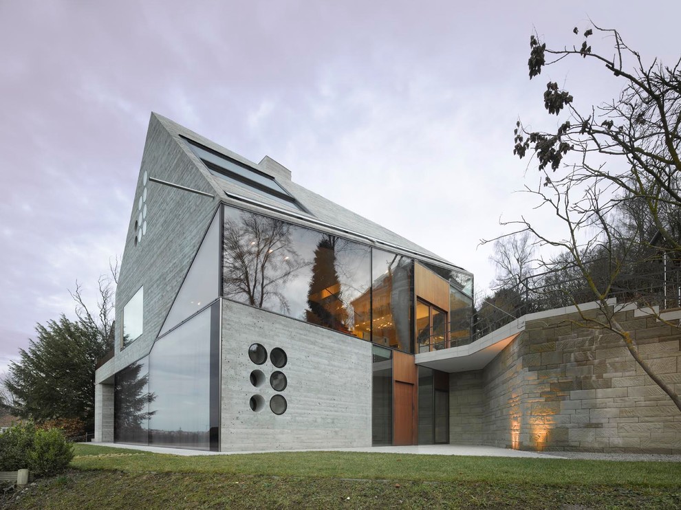 Dreistöckiges, Mittelgroßes Modernes Haus mit grauer Fassadenfarbe, Satteldach und Betonfassade in Stuttgart