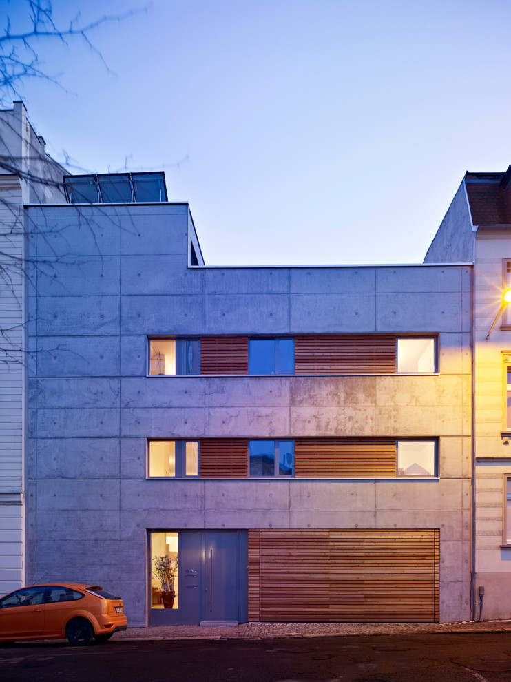 Diseño de fachada gris industrial de tamaño medio de tres plantas con revestimiento de hormigón y tejado plano