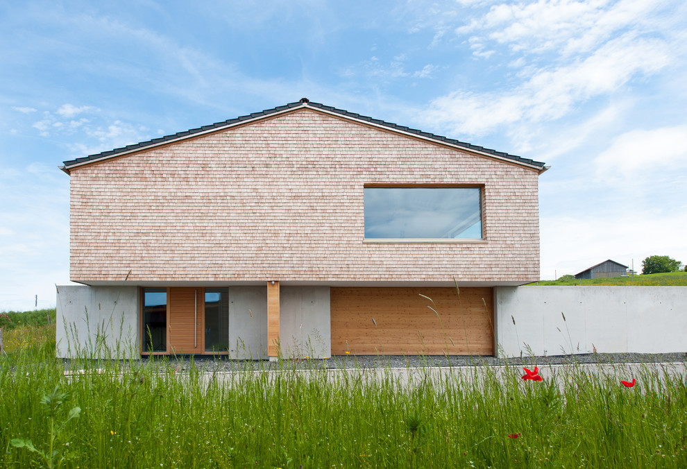 Cette photo montre une grande façade de maison grise tendance en bois à un étage avec un toit à deux pans et un toit en tuile.